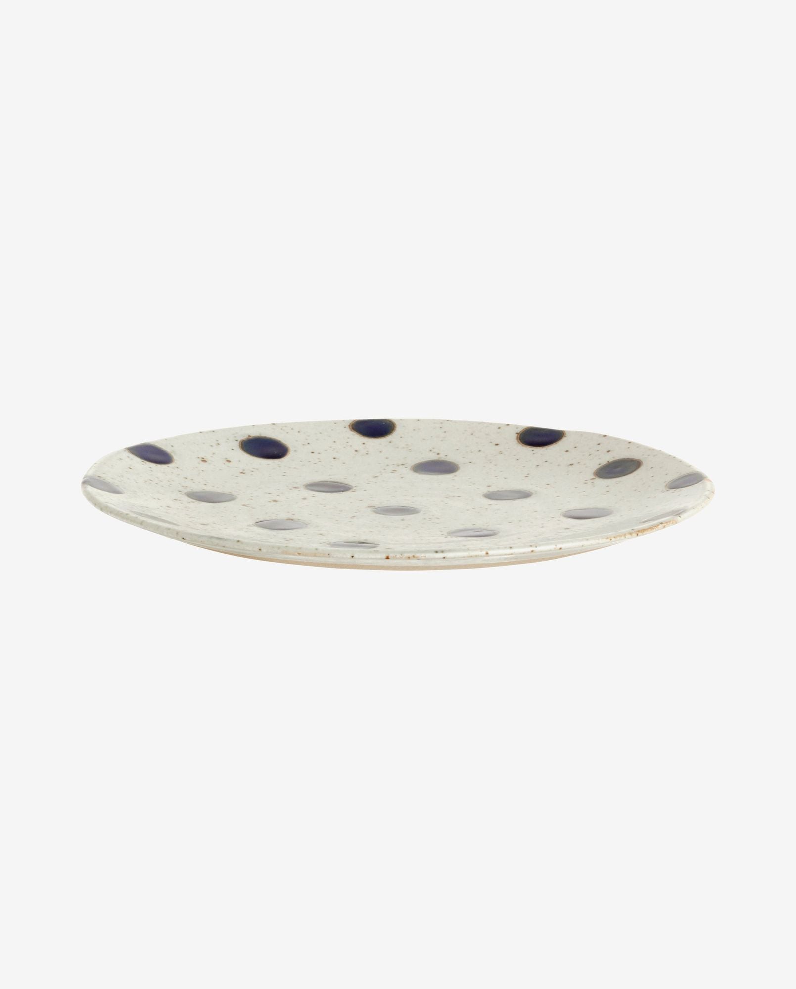 White ceramic plate with blue polka dots and speckled design on light background