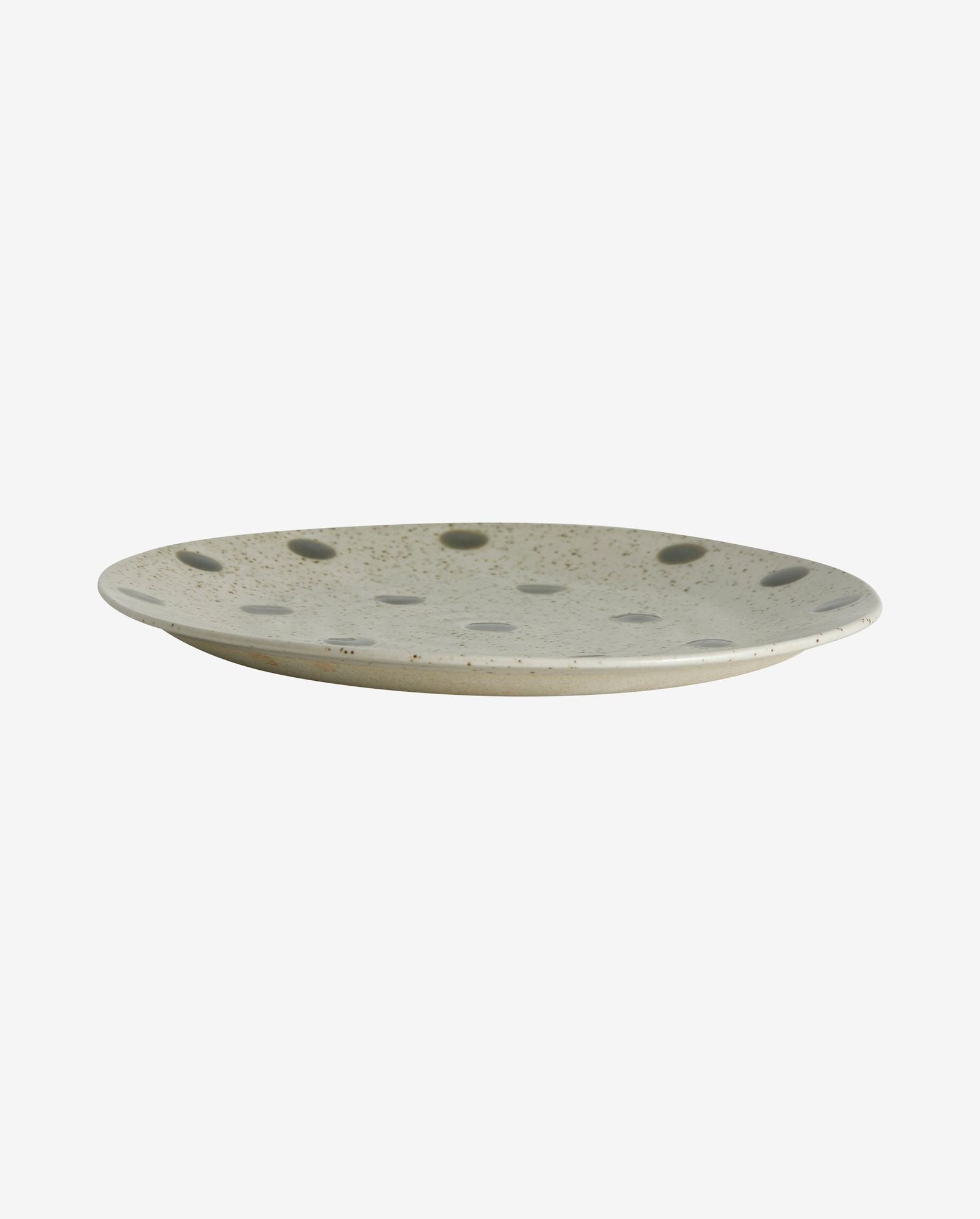 Ceramic beige plate with black polka dots and speckled design isolated on white