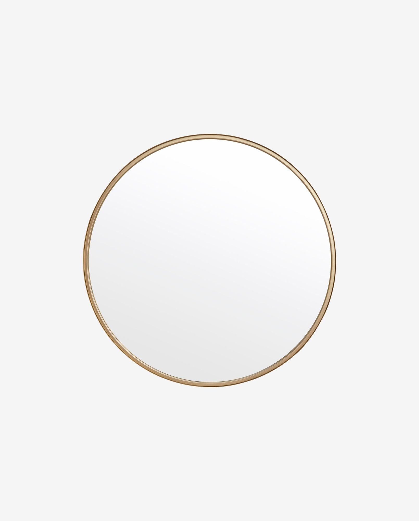 Round wall mirror with thin gold metal frame on white background