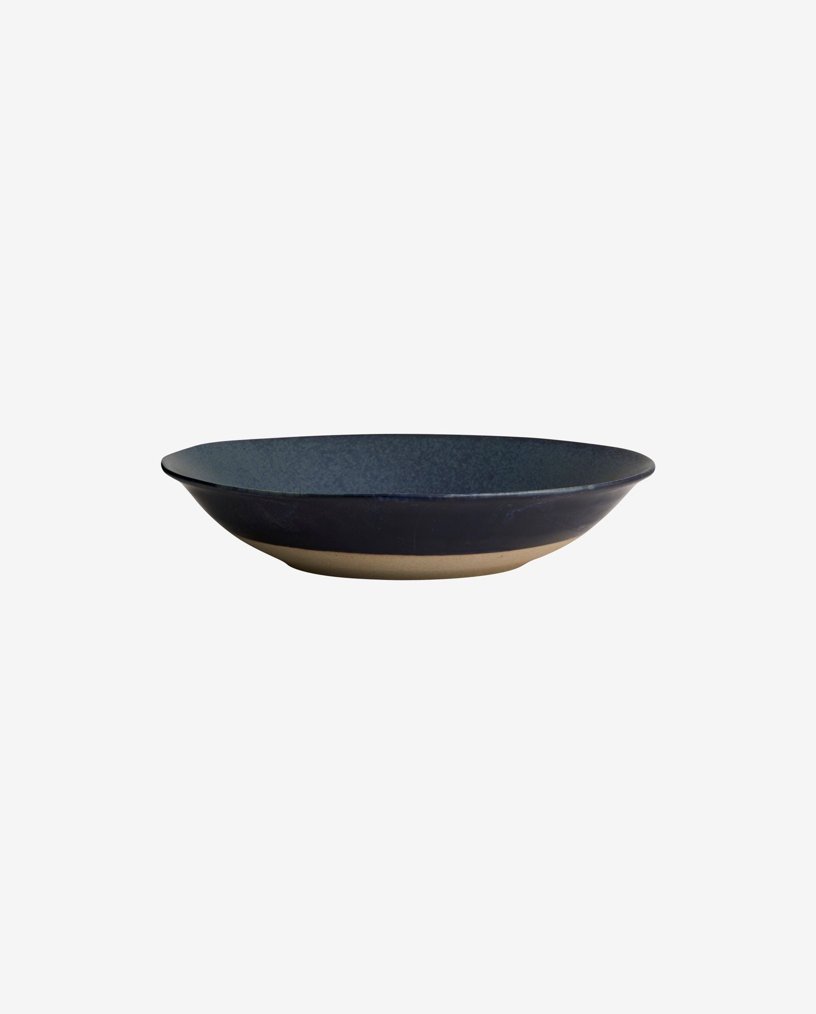 Handcrafted dark blue ceramic bowl with natural clay base on white background
