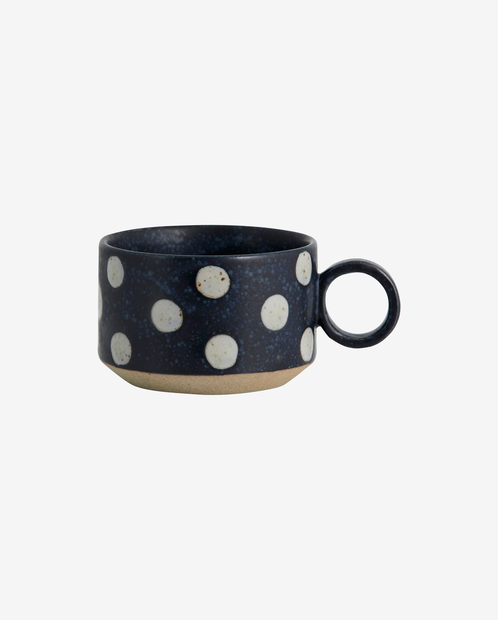 Dark blue ceramic cup with white polka dots and round handle on white background